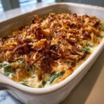A creamy, baked green bean casserole topped generously with crispy fried onions, ready to serve.