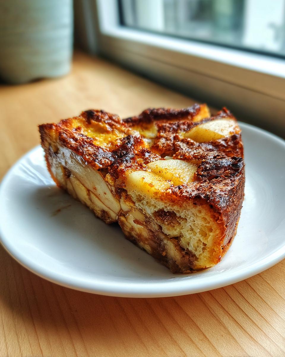 Close-up of a thick slice of baked Apple Cinnamon French Toast with caramelized edges and visible apple pieces.