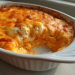 Close-up of creamy, cheesy Buffalo chicken dip baked golden brown in a white casserole dish.
