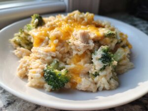 A close-up serving of creamy chicken broccoli rice casserole topped with melted cheddar cheese.