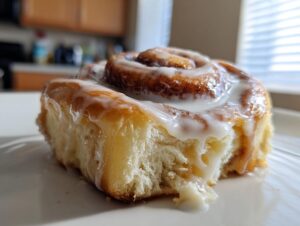 A single, fluffy cinnamon roll with thick, dripping white icing, made using cinnamon rolls with heavy cream.