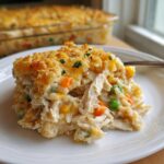 A close-up of a creamy serving of chicken and rice casserole with vegetables and a crunchy topping.