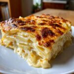 A close-up of a thick, layered slice of potatoes au gratin with a golden-brown, bubbly cheese crust.