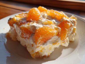 Close-up of a creamy slice of mandarin orange salad topped with bright orange segments.