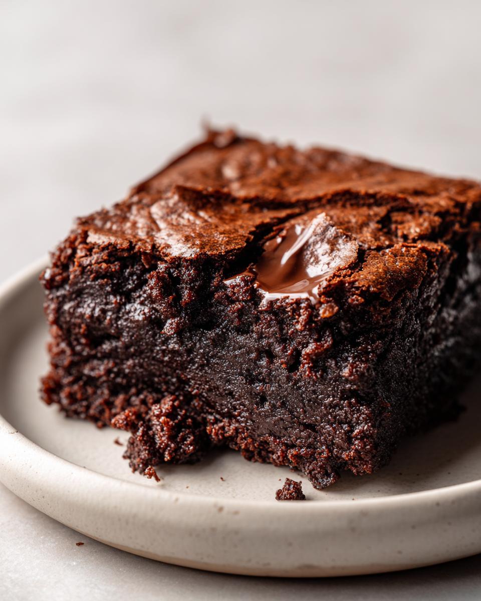 Close-up of a rich, fudgy slice of sweet potato brownies with a molten chocolate chip on top.
