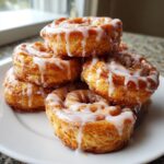A close-up stack of golden brown cinnamon roll bites drizzled with white icing.