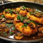 Four breaded cutlets of Chicken Marsala simmering in a rich brown mushroom sauce, garnished with fresh parsley.