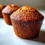 Close-up, macro shot of a perfectly baked, golden brown honey bran muffin showing its textured top.