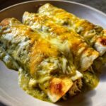Close-up of three delicious green chile chicken enchiladas covered in melted white and yellow cheese.