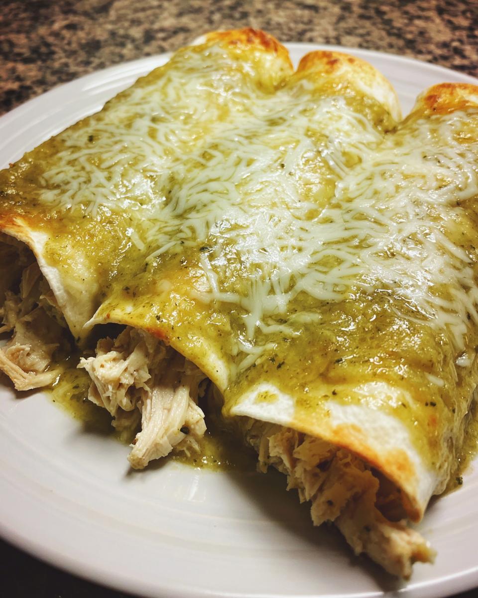 Close-up of three green chile chicken enchiladas smothered in green sauce and melted white cheese.