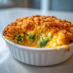 Close-up of a single serving broccoli cheese casserole with melted cheese and a crunchy golden breadcrumb topping.