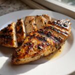 Juicy, sliced grilled chicken breast coated in herbs, showing grill marks from the grilled chicken marinade.