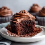 Close-up of an easy chocolate cupcakes with a bite taken out, showing the moist dark crumb and rich chocolate frosting.