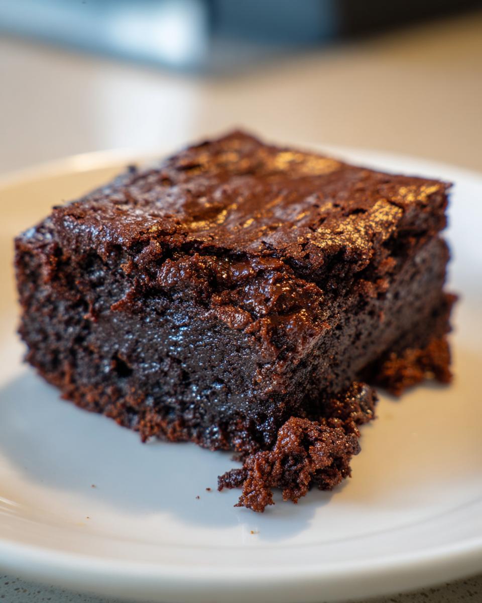 Close-up of a rich, dark chocolate square of sweet potato brownies on a white plate.