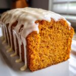 Close-up of a slice of ultra-moist sweet potato pound cake topped with thick, dripping vanilla glaze.