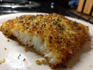 Close-up of a perfectly cooked parmesan crusted tilapia fillet showing flaky white fish inside and a golden, crispy topping.