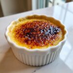 Close-up of a classic Creme Brulee with a perfectly caramelized, dark amber sugar crust.