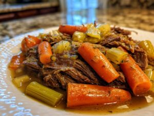Close-up of tender shredded pot roast with chunky carrots and celery, perfect for Sunday dinner ideas.