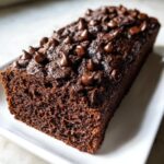 A moist, dark chocolate banana bread loaf topped generously with melted chocolate chips.