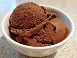 Close-up of two scoops of rich, dark brown chocolate pudding served in a small white bowl.