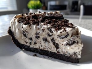 A generous slice of creamy, no-bake Oreo pie featuring a dark chocolate crust and whipped filling loaded with cookie pieces.