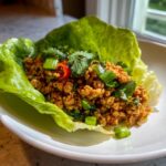 A single serving of flavorful Thai chicken lettuce wraps filling topped with cilantro and scallions.