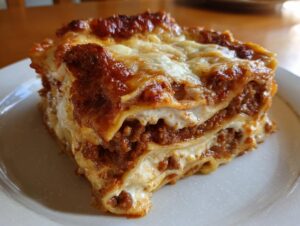 A close-up, generous slice of ultimate lasagna showing layers of pasta, rich meat sauce, and melted cheese.