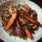 Close-up of a bright veggie lentil salad featuring roasted carrots, red onion wedges, and brown lentils, garnished with parsley.