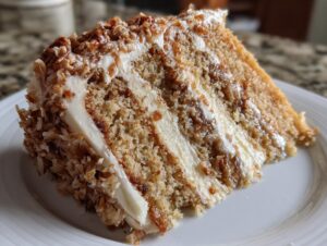 A close-up of a moist slice of white German chocolate cake layered with cream frosting and toasted coconut pecan topping.