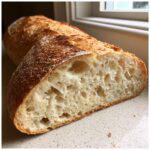 Close-up of the airy, open crumb structure inside a freshly baked loaf of french bread.
