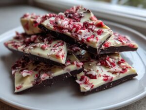 A stack of dark and white chocolate peppermint bark pieces topped with crushed candy canes.