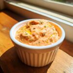 Close-up of creamy, orange-hued burger sauce drizzled with oil and herbs in a white ramekin.