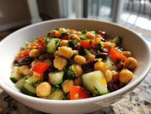 Close-up of a vibrant bean salad featuring chickpeas, kidney beans, cucumber, and tomato in a white bowl.