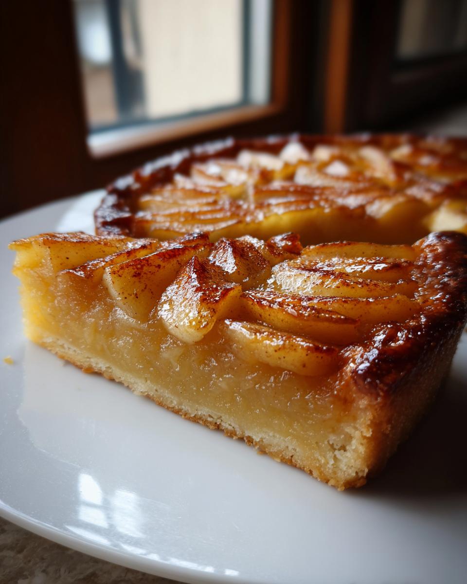 Close-up of a thick slice of amazing apple tart showing caramelized apple slices and a buttery crust.