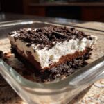A close-up of a slice of amazing dirt cake with layers of chocolate pudding, whipped topping, and crushed cookies.