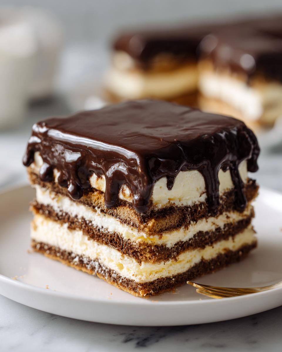 A square slice of layered eclair cake featuring chocolate cake, vanilla cream, and rich chocolate ganache topping.