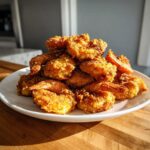 A generous mound of golden brown, crispy fried shrimp stacked high on a white plate.
