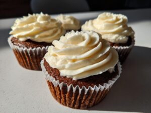 Close-up of three amazing gingerbread cupcakes topped with thick swirls of cream cheese frosting.