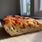 Close-up of a thick, cheesy slice showing the airy interior of the keto pizza crust.