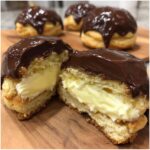 Close-up of a Boston Cream Pie Cookie cut in half showing vanilla cream filling and chocolate ganache topping.