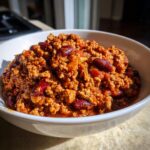 Close-up of a white bowl filled with hearty, rich high protein chili featuring ground meat and visible kidney beans.