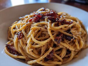 Close-up of creamy spaghetti tossed with rich caramelized onion pasta sauce and dark, sweet onion pieces.