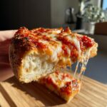 A thick slice of homemade pizza being pulled away, showing incredible cheese stretch and a fluffy crust.