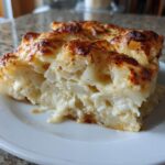 A close-up of a creamy, cheesy slice of scalloped potatoes with a golden-brown, bubbly crust.