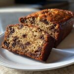 Two slices of moist chocolate chip banana bread recipe on a white plate, showing rich texture.