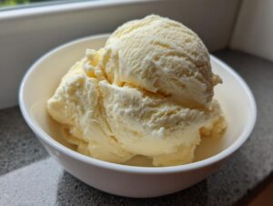 Two generous scoops of creamy, pale yellow banana ice cream served in a white bowl.
