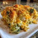 A close-up serving of creamy Chicken Divan casserole featuring melted cheddar cheese, broccoli florets, and a golden breadcrumb topping.