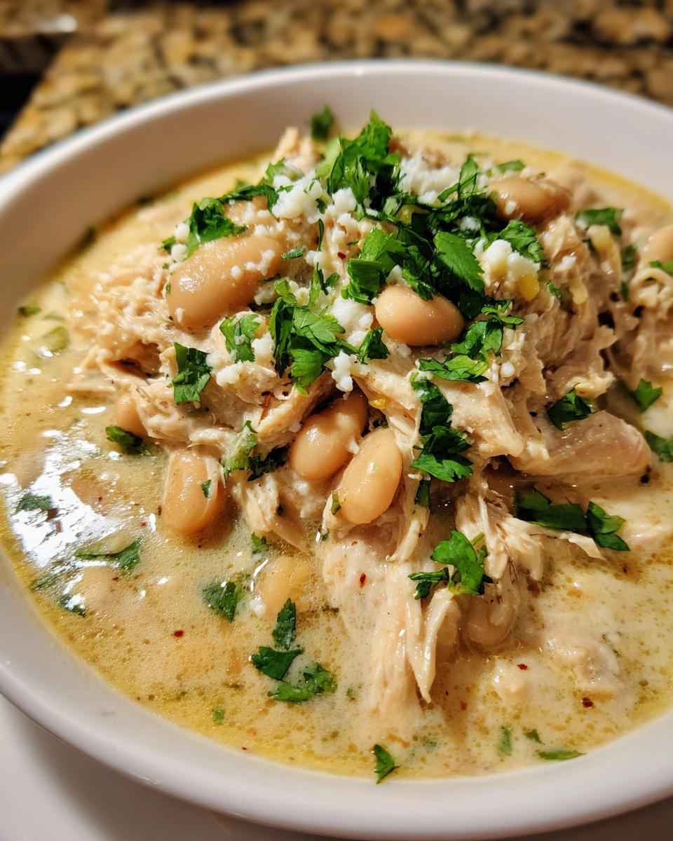 Close-up of a bowl of creamy white chicken chili recipe, featuring shredded chicken, white beans, and fresh cilantro.