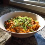 A white bowl filled with savory egg roll in a bowl mixture, topped generously with sliced green onions and sesame seeds.