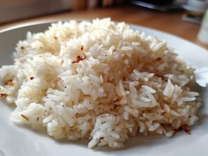 Close-up of a mound of fluffy white butter rice with golden toasted bits on a white plate.